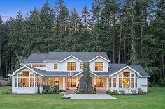 a large white house with lots of windows in the front yard and trees behind it