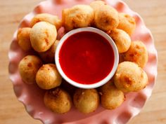 a pink plate topped with fried food next to a red sauce