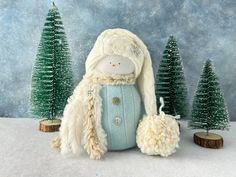 a stuffed animal is standing in the snow next to some small trees and pine cones