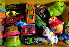 many toy cars and trucks are stacked on top of each other in a bin together