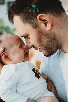 a man holding a baby and kissing it's face with his mouth open in front of him