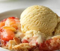 a bowl filled with ice cream and strawberry cobbler on top of a white table