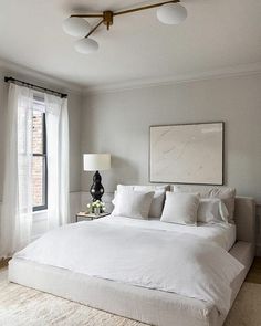 a large white bed sitting in a bedroom next to a window