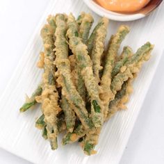 fried green beans and dipping sauce on a white plate