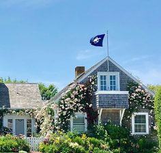 a house with flowers on the front yard and a flag flying in the air above it