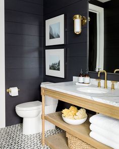 a white toilet sitting next to a sink in a bathroom under two pictures on the wall