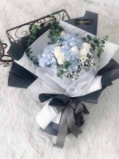 a bouquet of flowers sitting on top of a white blanket next to a box filled with blue and white flowers