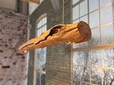 a piece of wood hanging from a string in front of a brick wall and window