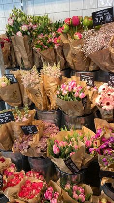 many different types of flowers on display in buckets at a flower shop for sale