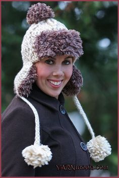 a woman wearing a knitted hat with pom poms