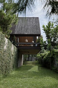 a house that is sitting in the middle of some bushes and grass with an open balcony