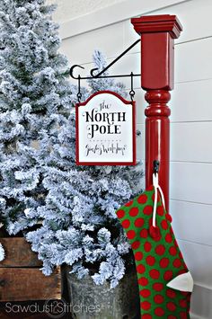 a christmas stocking hanging from a red pole next to a tree with a sign that says the north pole