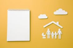 a notepad, paper cutouts and a family's house on a yellow background