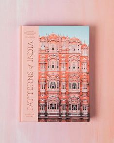 a pink book sitting on top of a wooden table next to a white and orange wall