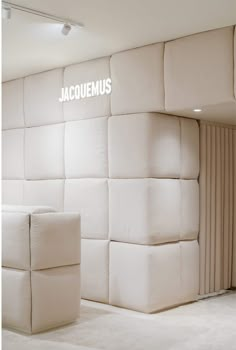 a white couch sitting in front of a wall with the word jacquemus on it