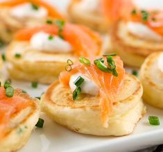 small appetizers with salmon and cream cheese are on a white plate, ready to be eaten