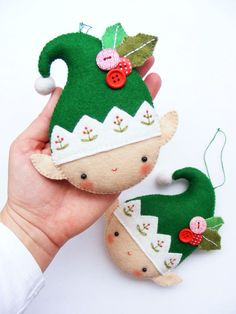 two handmade christmas ornaments are being held by someone's hand, one is green and the other is red