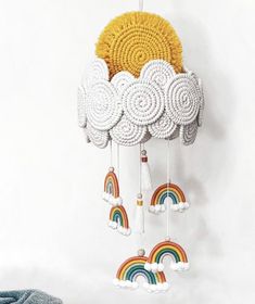 a crocheted sun and rainbow mobile hanging on a wall