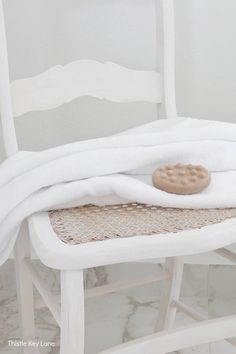 a white chair with a blanket on it and a cookie sitting on top of it