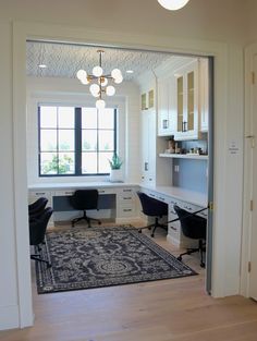 an open door leading to a home office with desks and chairs in the corner