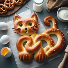 a cat shaped pretzel sitting on top of a piece of paper next to eggs