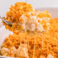 a spoon full of macaroni and cheese being lifted from a casserole dish