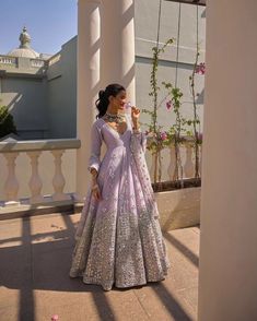 a woman in a pink and silver gown standing on a balcony next to some flowers