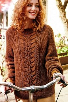 a woman standing next to a bike wearing a brown sweater