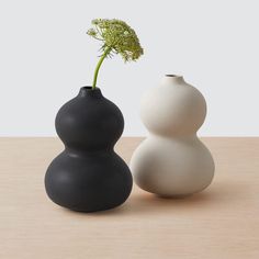 two black and white vases sitting on top of a wooden table next to each other