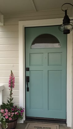 a blue front door on a white house with potted flowers in the foreground