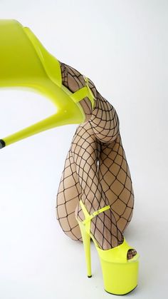 a woman in fishnet stockings and high heels is holding a neon yellow plastic chair