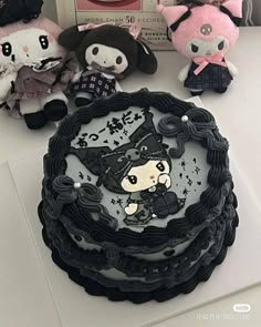 there are many stuffed animals sitting on top of the cake, which is decorated with black and white frosting