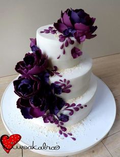 a three tiered cake with purple flowers on top