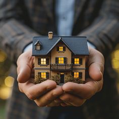 a person holding a house in their hands with the light shining on it's windows