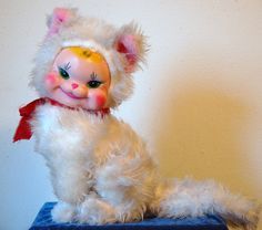 a small white stuffed animal sitting on top of a blue box with a red ribbon around it's neck