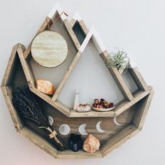 a wooden shelf with some plants and other items on it's sides, in front of a white wall