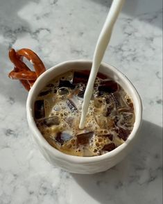 a cup of hot chocolate with pretzels in it and milk being poured into the mug