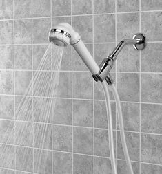 a shower head with water running from it's spout in a tiled wall