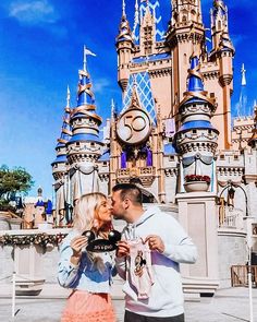 a man and woman kissing in front of a castle