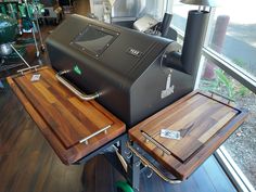 a large black grill sitting on top of a wooden table next to a glass window