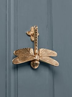 a gold dragonfly door knockle on a blue door