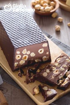 there are pieces of chocolate and nuts on the cutting board