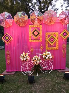 a pink wall with umbrellas and flowers on it in front of a white bicycle