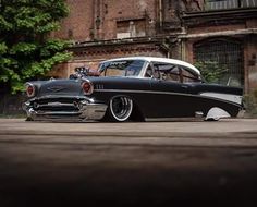 an old black and white car parked in front of a building