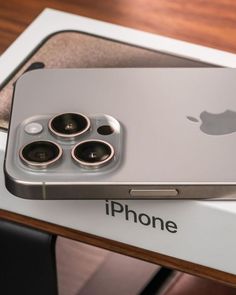 an iphone sitting on top of a box with its camera lens open and the back facing up