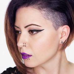 a woman with purple lipstick and piercings on her nose