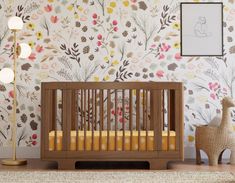 a baby's room with floral wallpaper and a wooden crib in the foreground