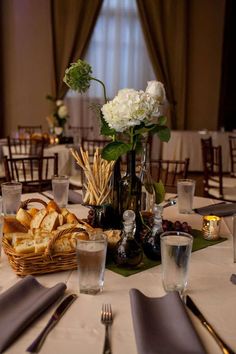 the table is set with silverware, wine glasses and breads in vases