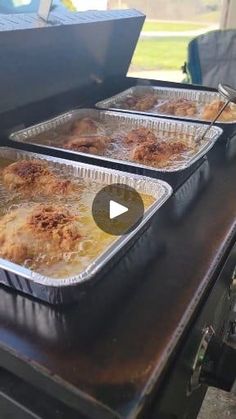 three pans filled with food sitting on top of an outdoor grill