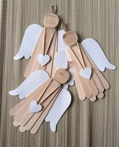 wooden spoons with white hearts and angel wings on top of a brown tablecloth